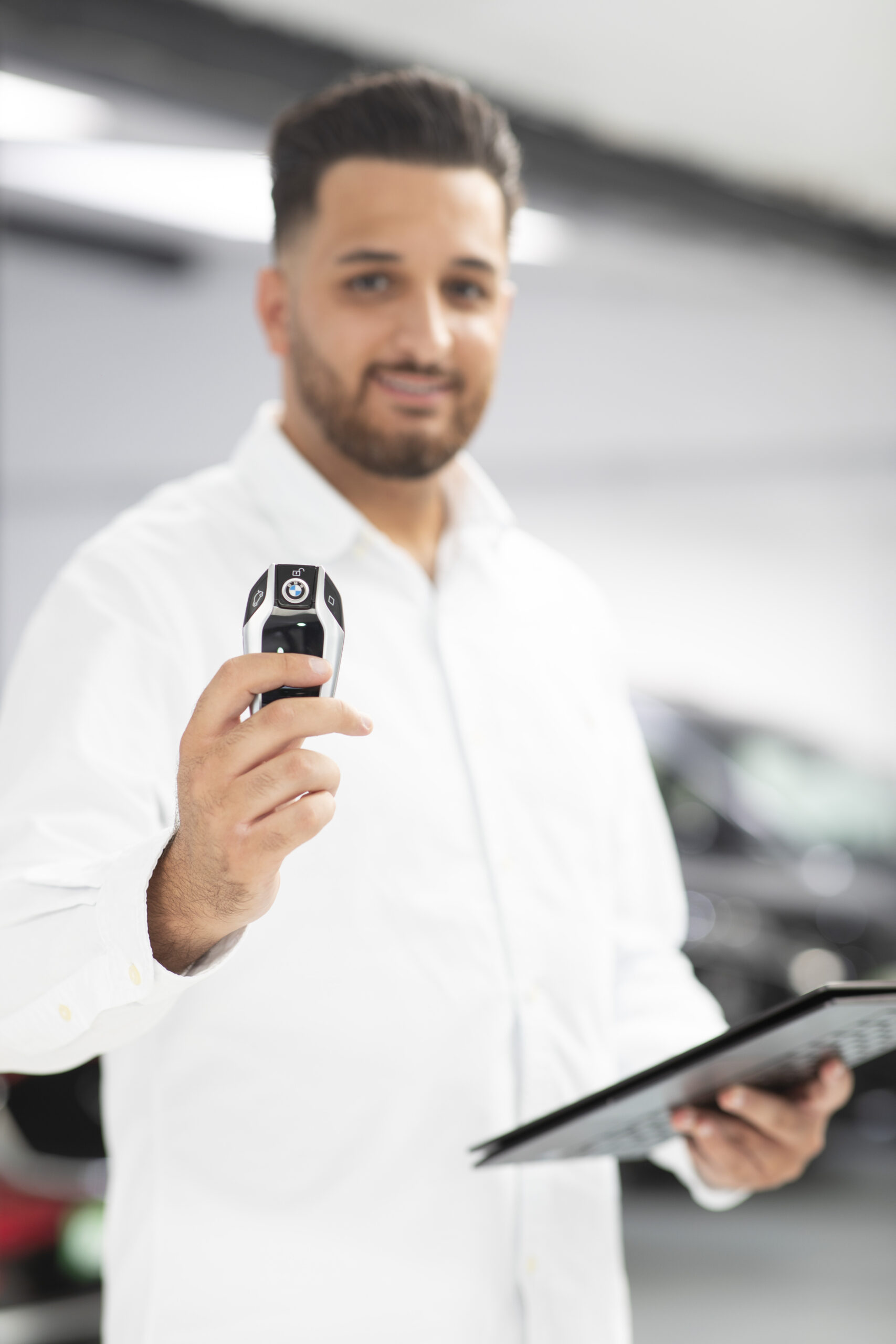 Mitarbeiter von iTrust Automobile präsentiert einen BMW-Fahrzeugschlüssel von einem Gebrauchtwagen im Autohaus in Solingen.