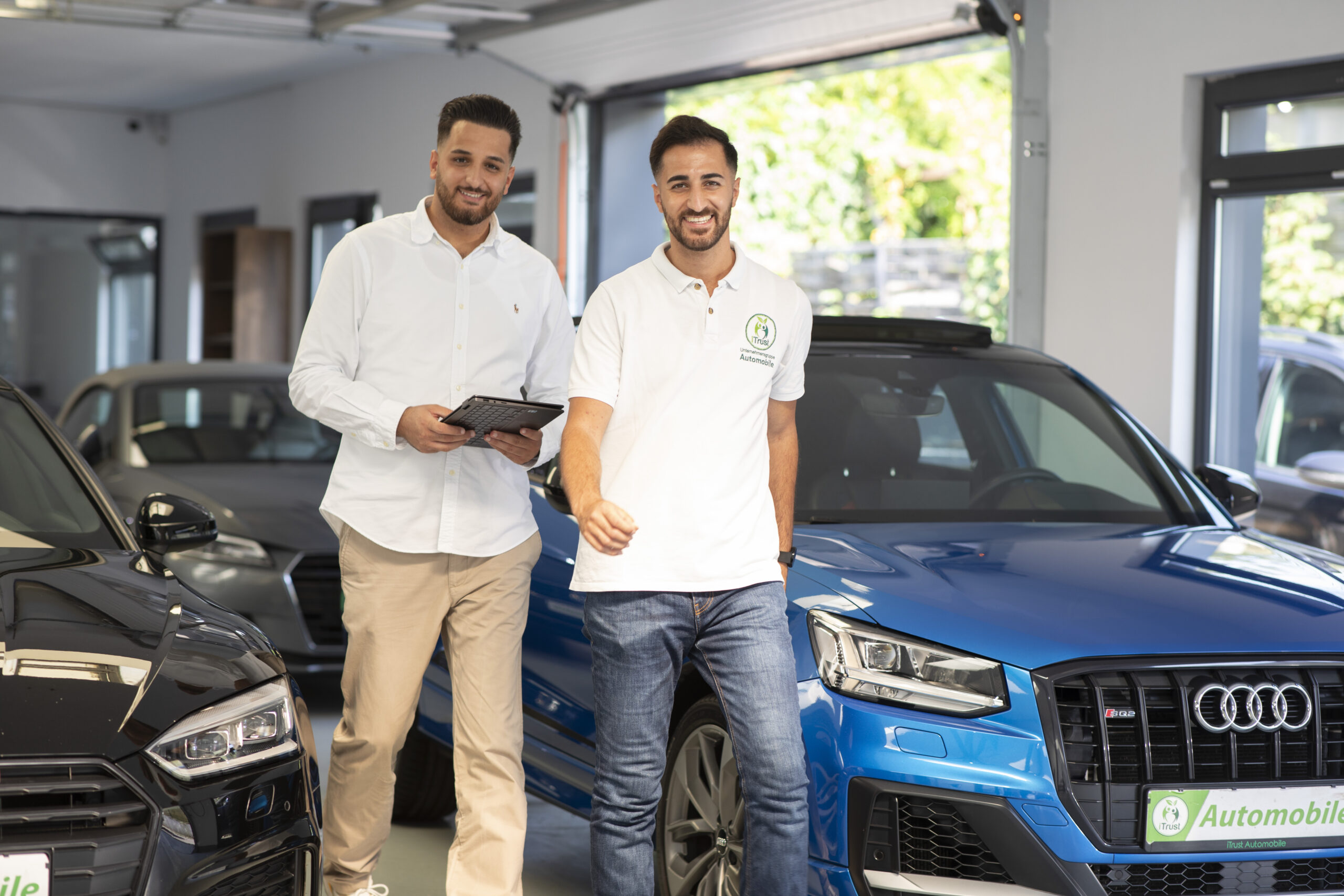 Sekan- und Suleyman Tün von iTrust Automobile zwischen hochwertigen Gebrauchtwagen im Autohaus in Solingen.