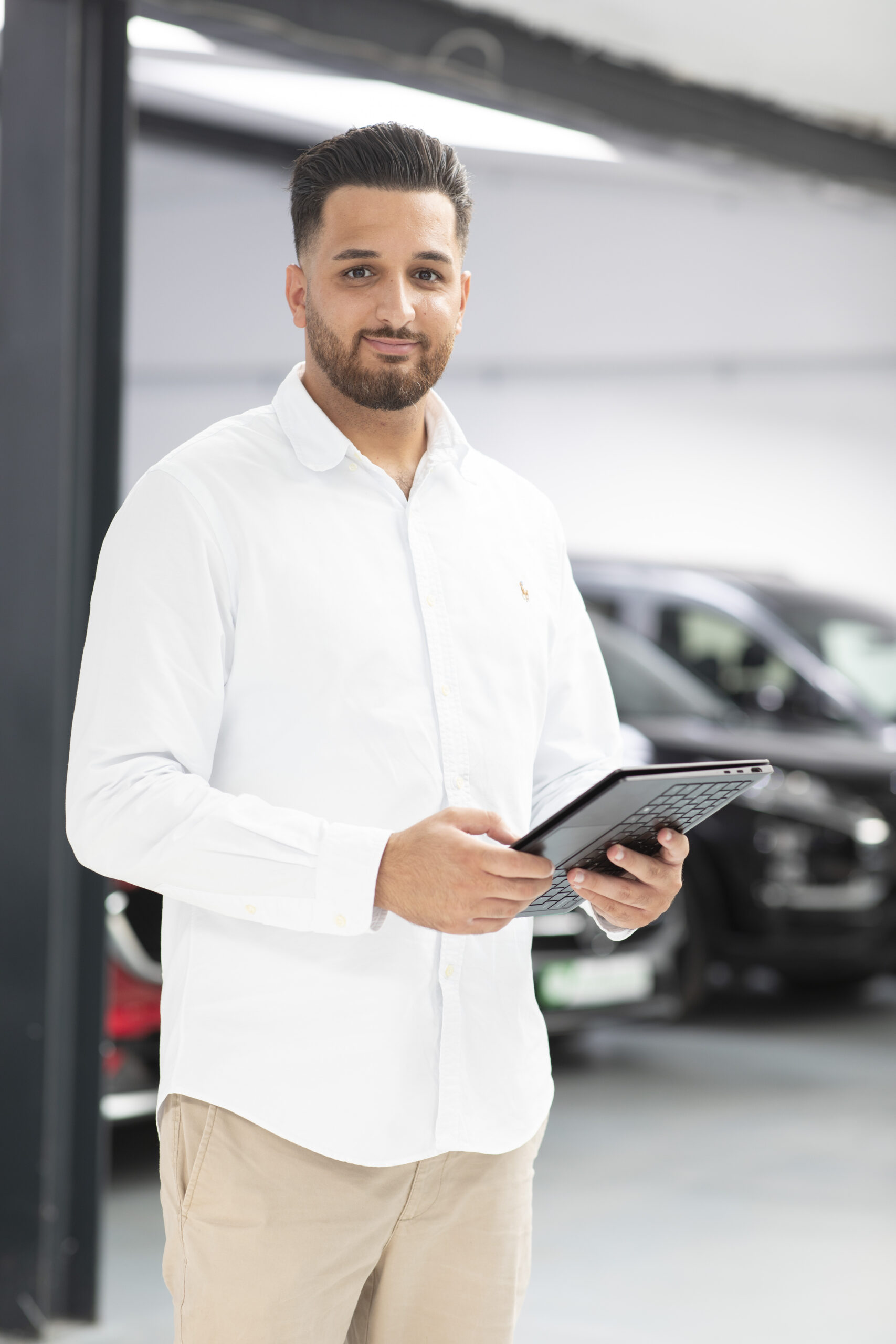 Sefkan Tün mit Tablet als Ansprechpartner für BMW Gebrauchtwagen bei iTrust Automobile in Solingen.